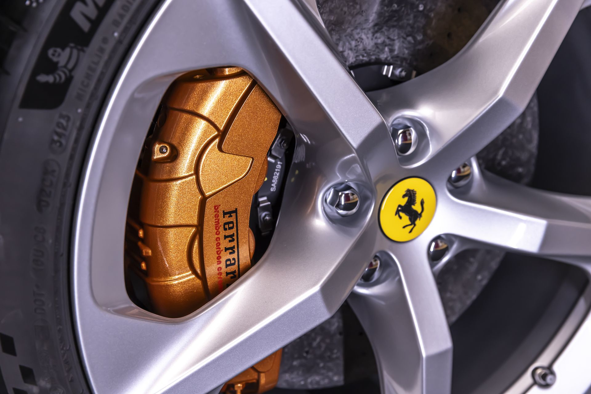 Vista cercana del icónico freno carbono-cerámico de Ferrari con pinza dorada.