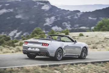 Vista trasera y lateral del Ford Mustang 2024 en carretera abierta.