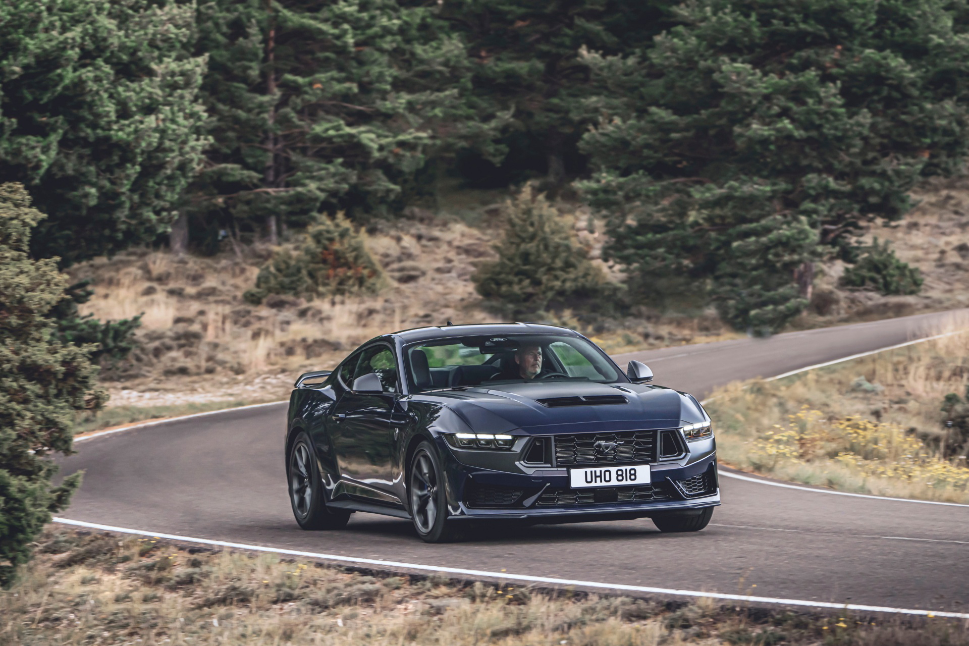 Vista lateral del Ford Mustang 2024 rodando con dinamismo por carretera de montaña