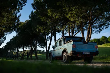 Perfil del Ineos Grenadier posando su robustez entre árboles