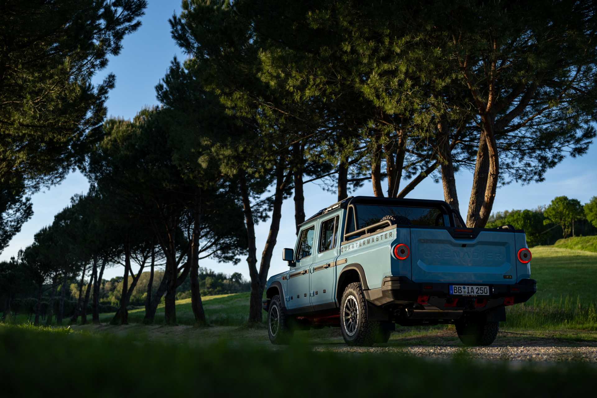 Perfil del Ineos Grenadier posando su robustez entre árboles