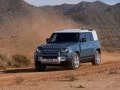 Vista delantera y lateral del Land Rover Defender 2024 en terreno arenoso.