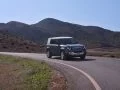 Vista dinámica del Land Rover Defender 2024 avanzando por carretera de montaña.