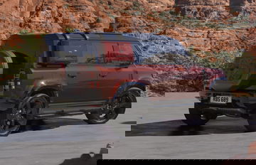 Vista lateral y trasera del Land Rover Defender Sedona Edition 2024 en entorno natural.