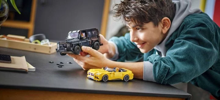 Un niño disfruta de un set de Lego Speed Champions, incluyendo un vehículo deportivo amarillo y un SUV negro.