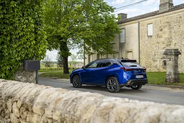 El Lexus UX 300h 2024 en su hábitat urbano, mostrando lineas laterales elegantes.
