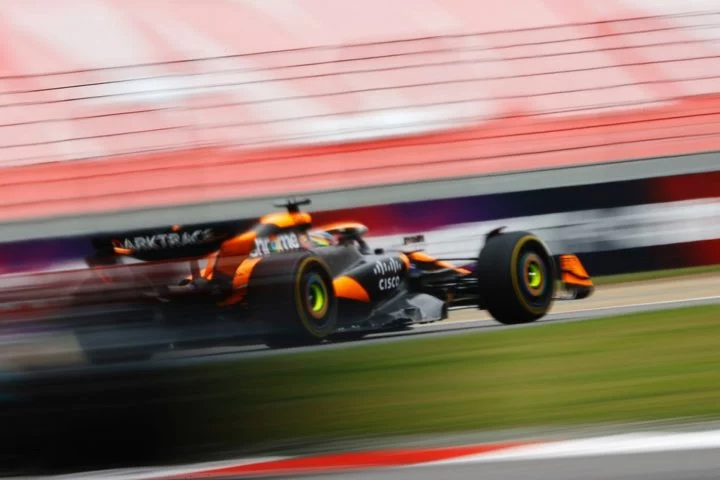 McLaren F1 en pista con una dinámica toma lateral mostrando velocidad y aerodinámica.