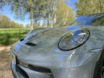 Vista detallada de la parte delantera del Porsche 911 GT3 Touring, destacando sus faros y tomas de aire.
