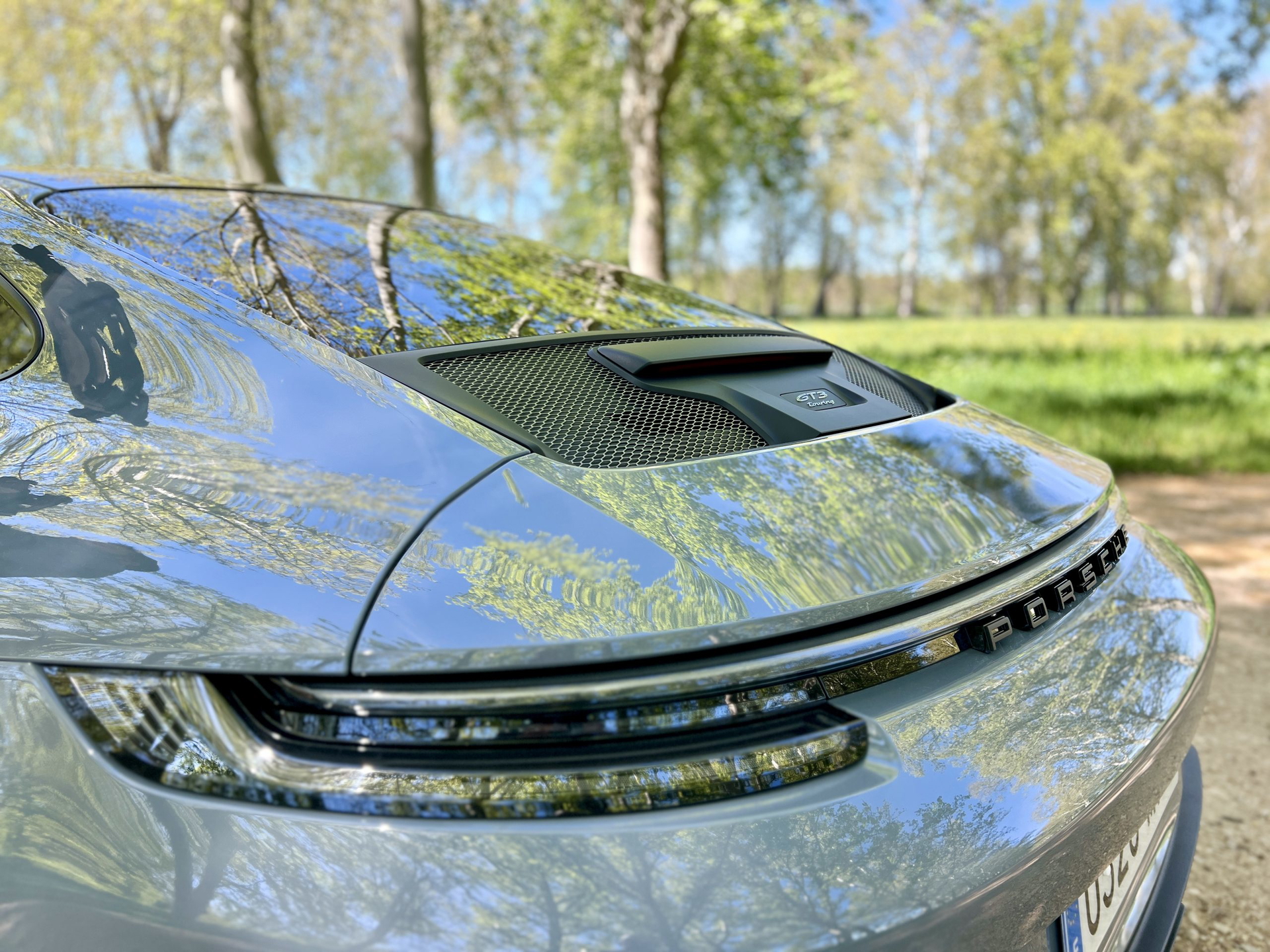Vista trasera del Porsche 911 GT3 Touring, énfasis en salida de aire y luces traseras.