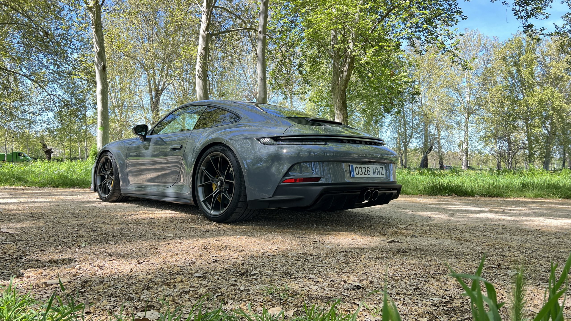 Vista angular trasera del Porsche 911 GT3 Touring aparcado en entorno natural.