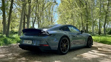 Vista trasera y lateral de un Porsche 911 GT3 Touring en escenario natural
