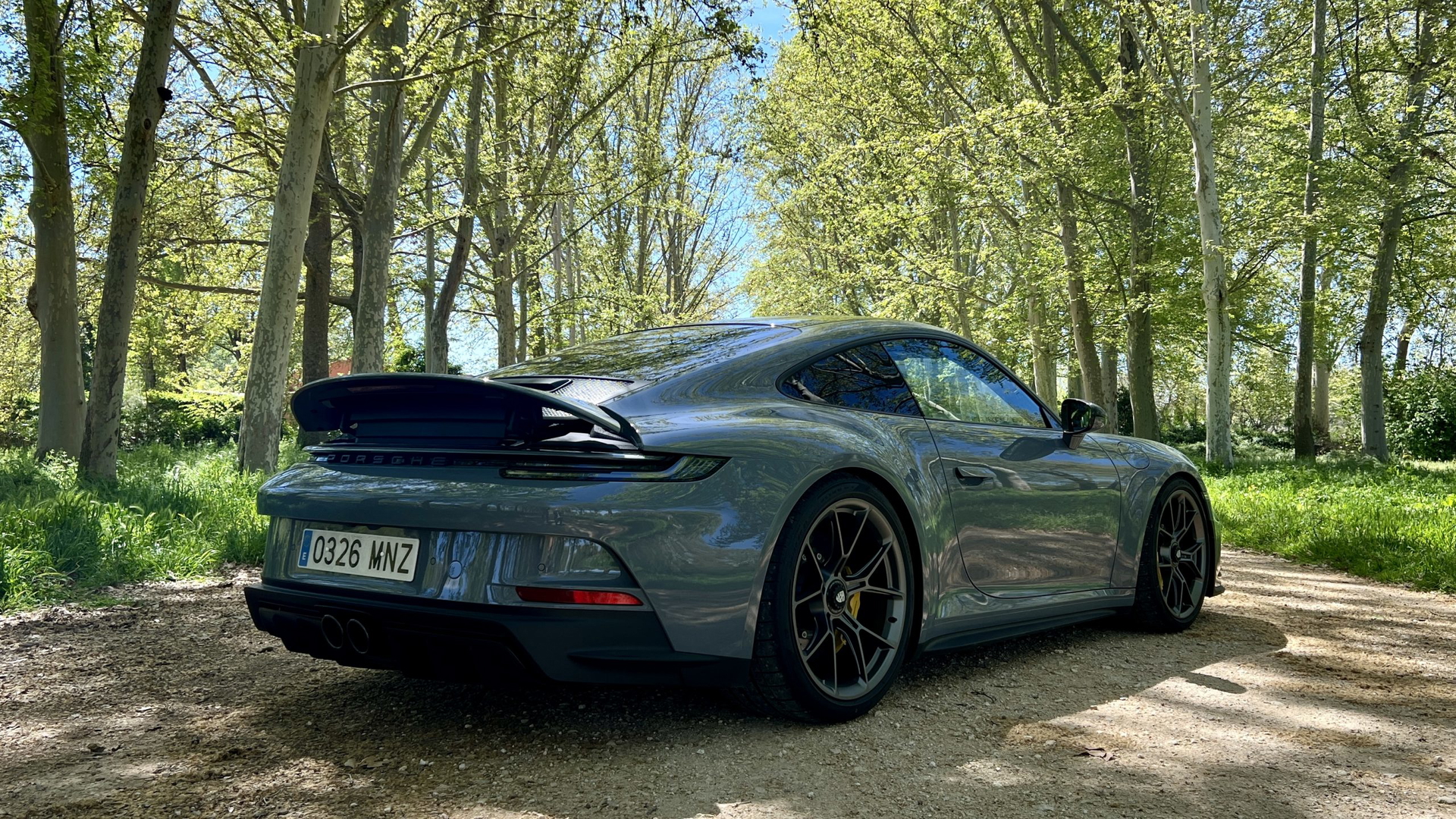 Vista trasera y lateral de un Porsche 911 GT3 Touring en escenario natural
