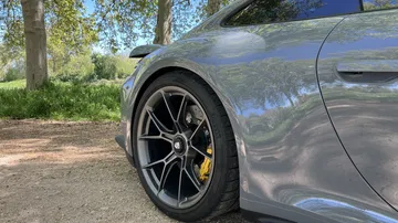 Rueda y carrocería lateral del Porsche 911 GT3 Touring, enfocando diseño y llantas.