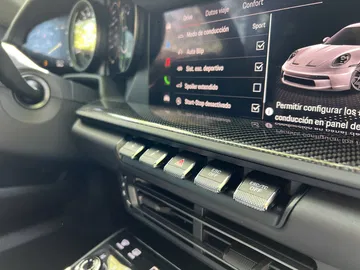 Vista enfocada de la consola central del Porsche 911 GT3 Touring, mostrando botones de control deportivo.