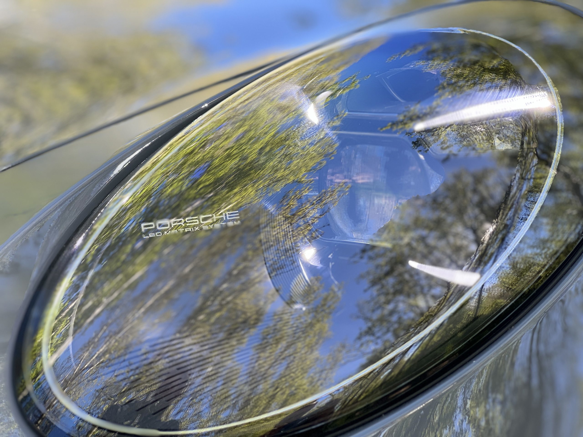 Primer plano del faro del Porsche 911 GT3 Touring que refleja su entorno.