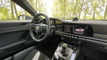 Vista interna del Porsche 911 GT3 Touring mostrando su elegante cabina y volante.