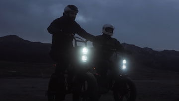 Dos e-bikes estilo scrambler destacando su iluminación delantera.