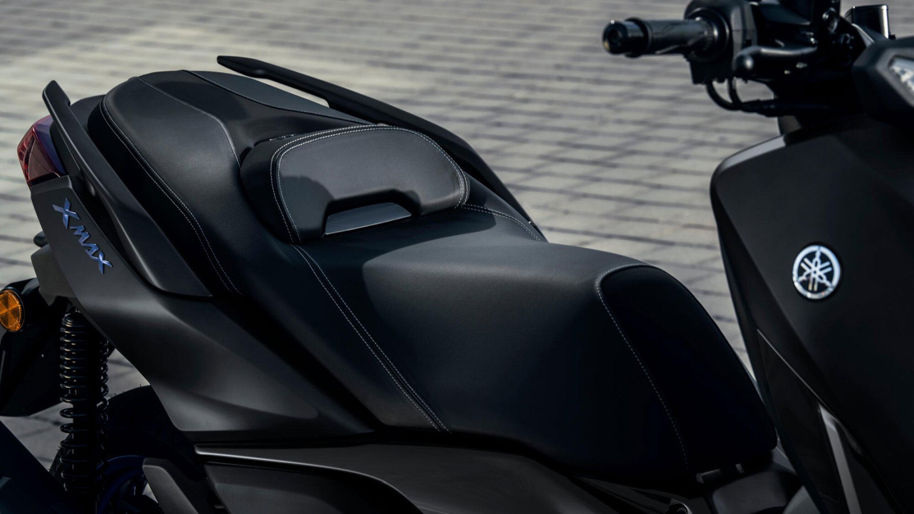 Vista lateral del asiento trasero de la Yamaha X-Max 125, destacando su ergonomía y acabados. Vista lateral del asiento trasero de la Yamaha X-Max 125, destacando su ergonomía y acabados.