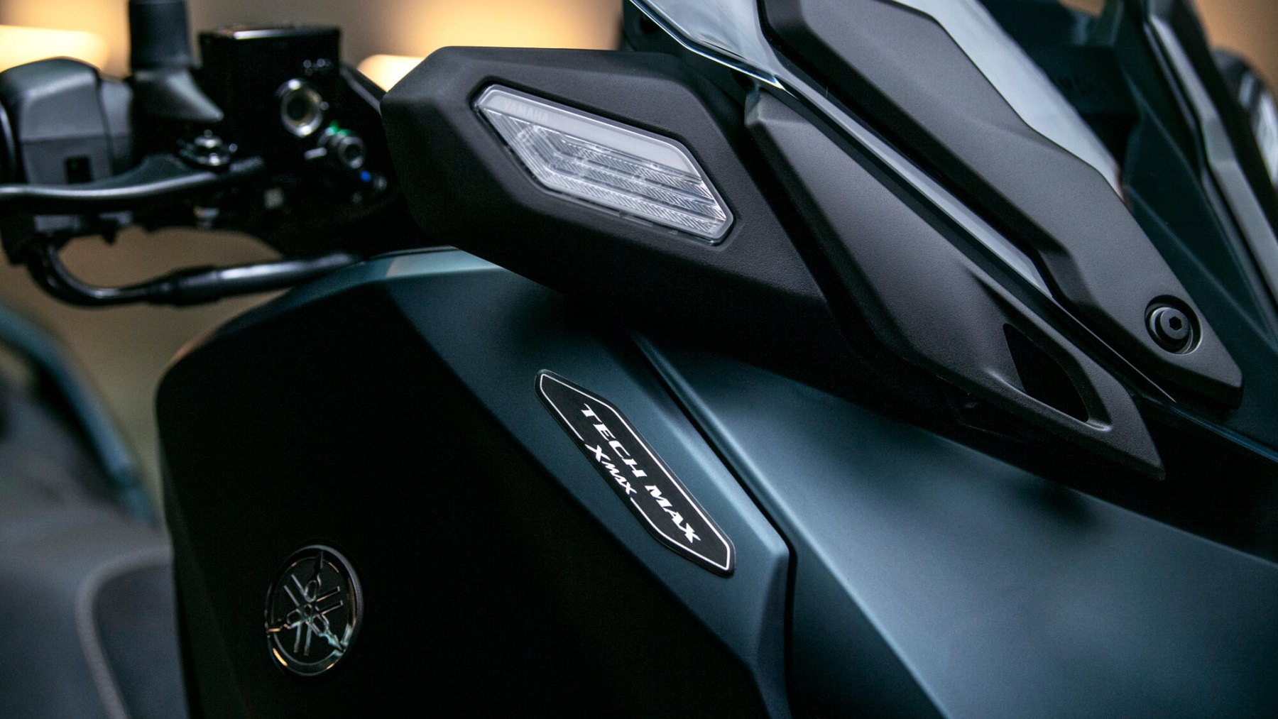 Vista del faro delantero y emblema de Yamaha X-Max 125cc, destacando su diseño moderno.