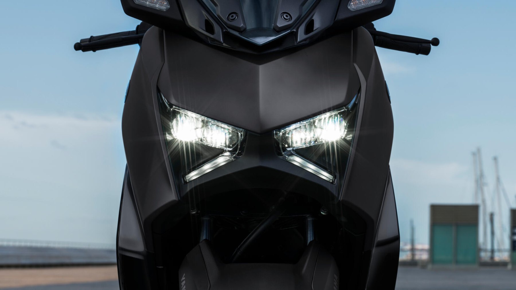 Vista frontal de la Yamaha X-Max 125cc mostrando su diseño de iluminación agresivo Vista frontal de la Yamaha X-Max 125cc mostrando su diseño de iluminación agresivo