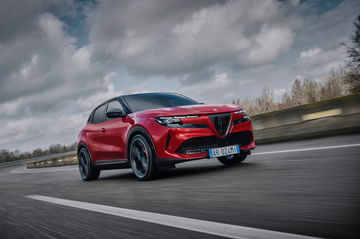 Vista dinámica trasera lateral del Alfa Romeo en movimiento, resaltando su diseño deportivo.