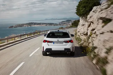 Vista dinámica del BMW M135 en carretera con diseño deportivo y etiqueta ECO.