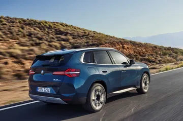 BMW X3 30e en movimiento, destacando su diseño lateral y eficiencia.