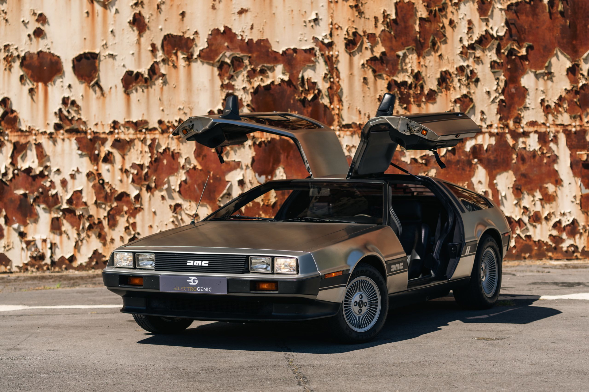 El clásico DeLorean DMC-12 reimaginado como vehículo eléctrico con puertas aladas abiertas.