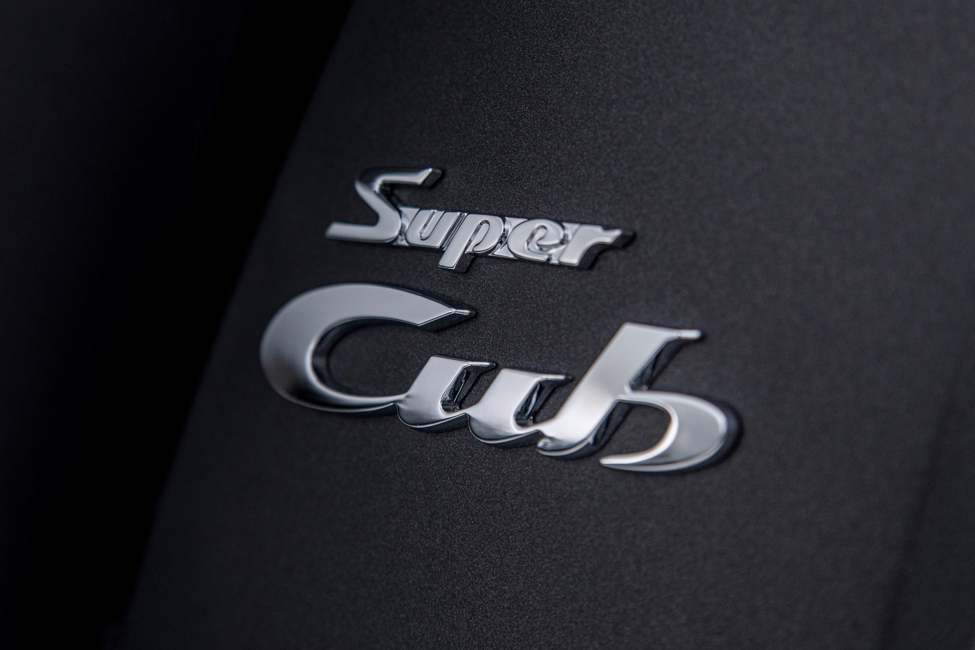 Vista cercana del icónico emblema 'Super Cub' de Honda, un sinónimo de eficiencia y confiabilidad.