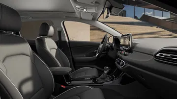 Vista interior delantera y lateral del Hyundai i30 Fastback 2024, mostrando elegancia y modernidad