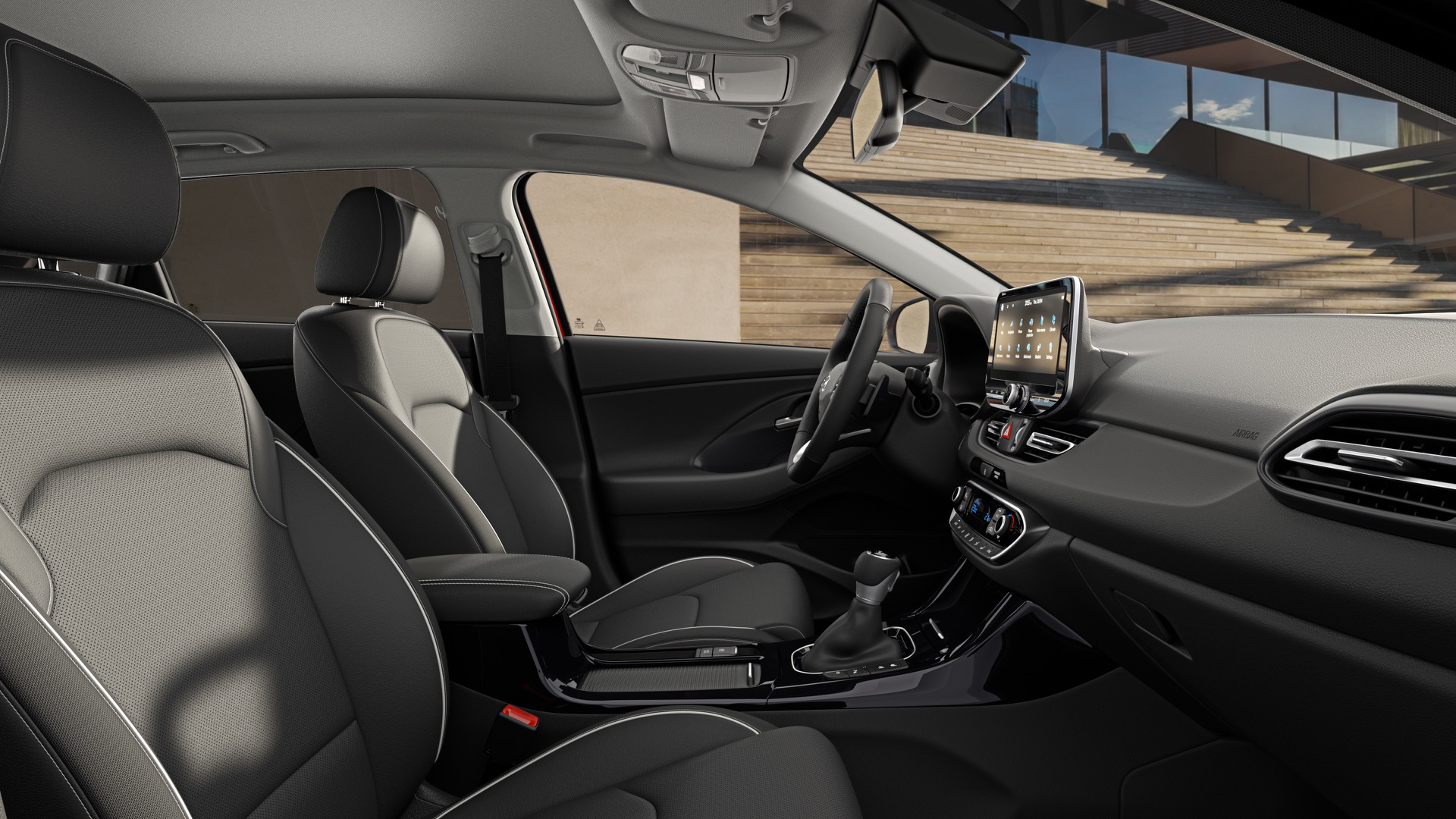 Vista interior delantera y lateral del Hyundai i30 Fastback 2024, mostrando elegancia y modernidad