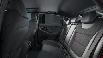 Vista interior trasera lateral del Hyundai i30 Fastback N Line 2024, mostrando asientos y acabados.