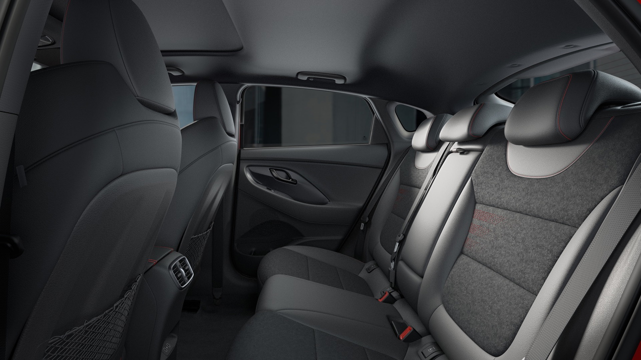 Vista interior trasera lateral del Hyundai i30 Fastback N Line 2024, mostrando asientos y acabados. Vista interior trasera lateral del Hyundai i30 Fastback N Line 2024, mostrando asientos y acabados.