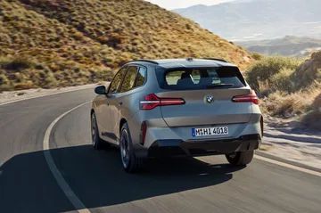 Vista dinámica de la nueva generación del BMW X3 en carretera, destaca diseño y líneas traseras.