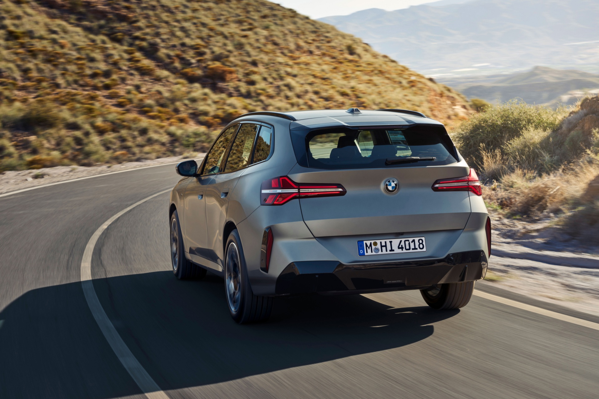 Vista dinámica de la nueva generación del BMW X3 en carretera, destaca diseño y líneas traseras.
