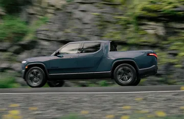 Vista dinámica lateral del Rivian R1T, mostrando su diseño robusto y moderno.