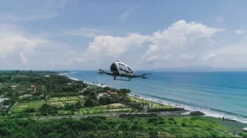 Vista lateral de un taxi volador autónomo en vuelo sobre costa