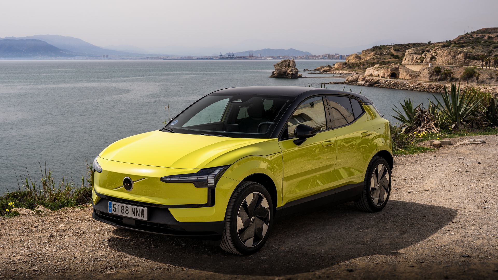 Volvo eléctrico amarillo destacando su diseño sueco en un paisaje costero.