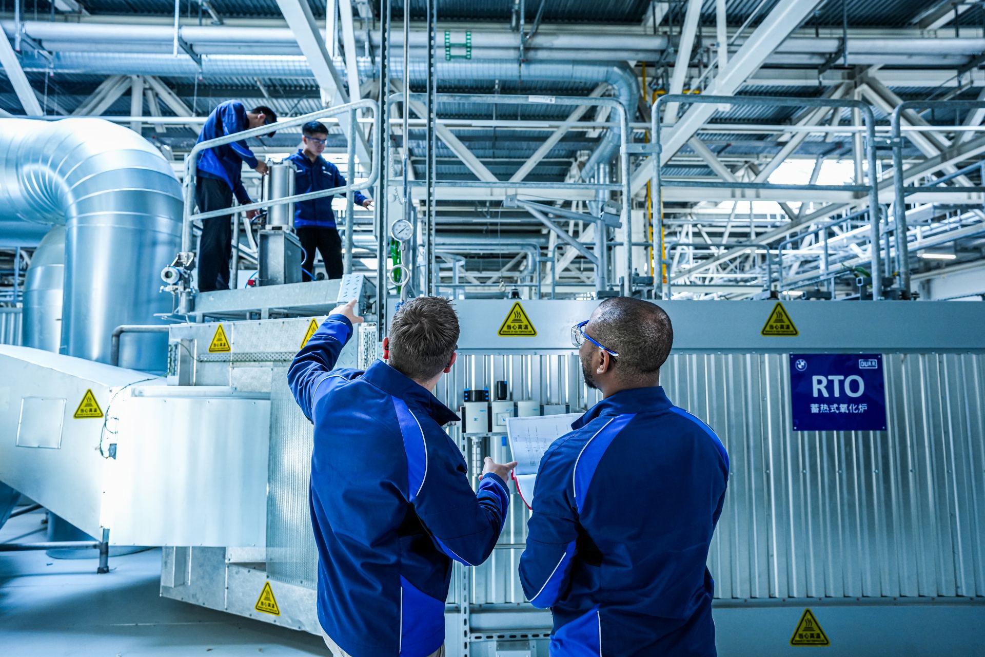 Imagen de profesionales inspeccionando maquinaria industrial, posible relación con fabricación de vehículos BMW.