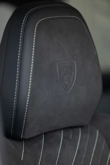 Detalle de tapicería y emblema de Peugeot en el respaldo del asiento.