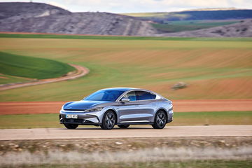 Perfil de coche eléctrico en carretera con paisaje campestre