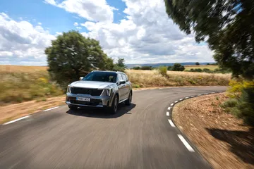 Kia Sorento 2024 en movimiento por carretera secundaria, imponente y elegante.