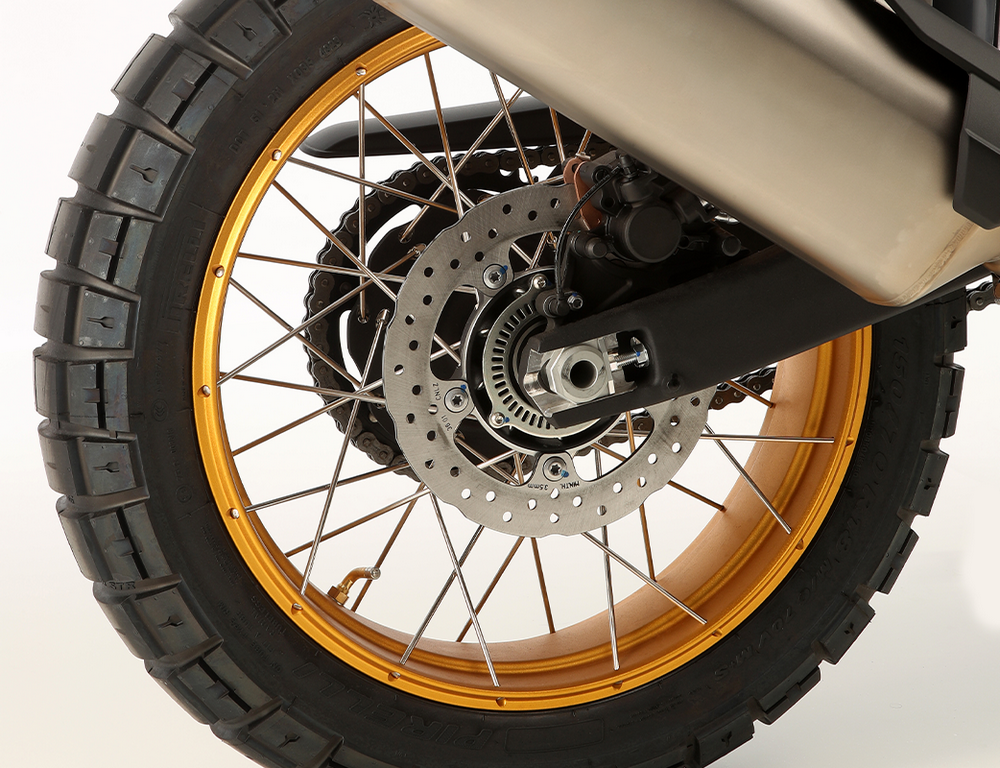 Primer plano de la rueda trasera con sistema de frenado de una moto trail.