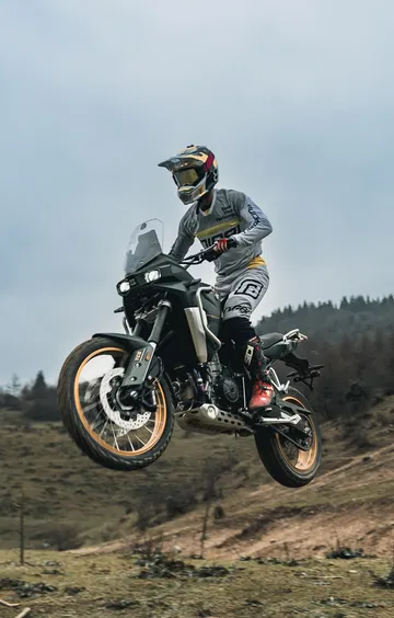 Trail Kove Moto 800X Pro en acción, suspendida en un salto con paisaje al fondo