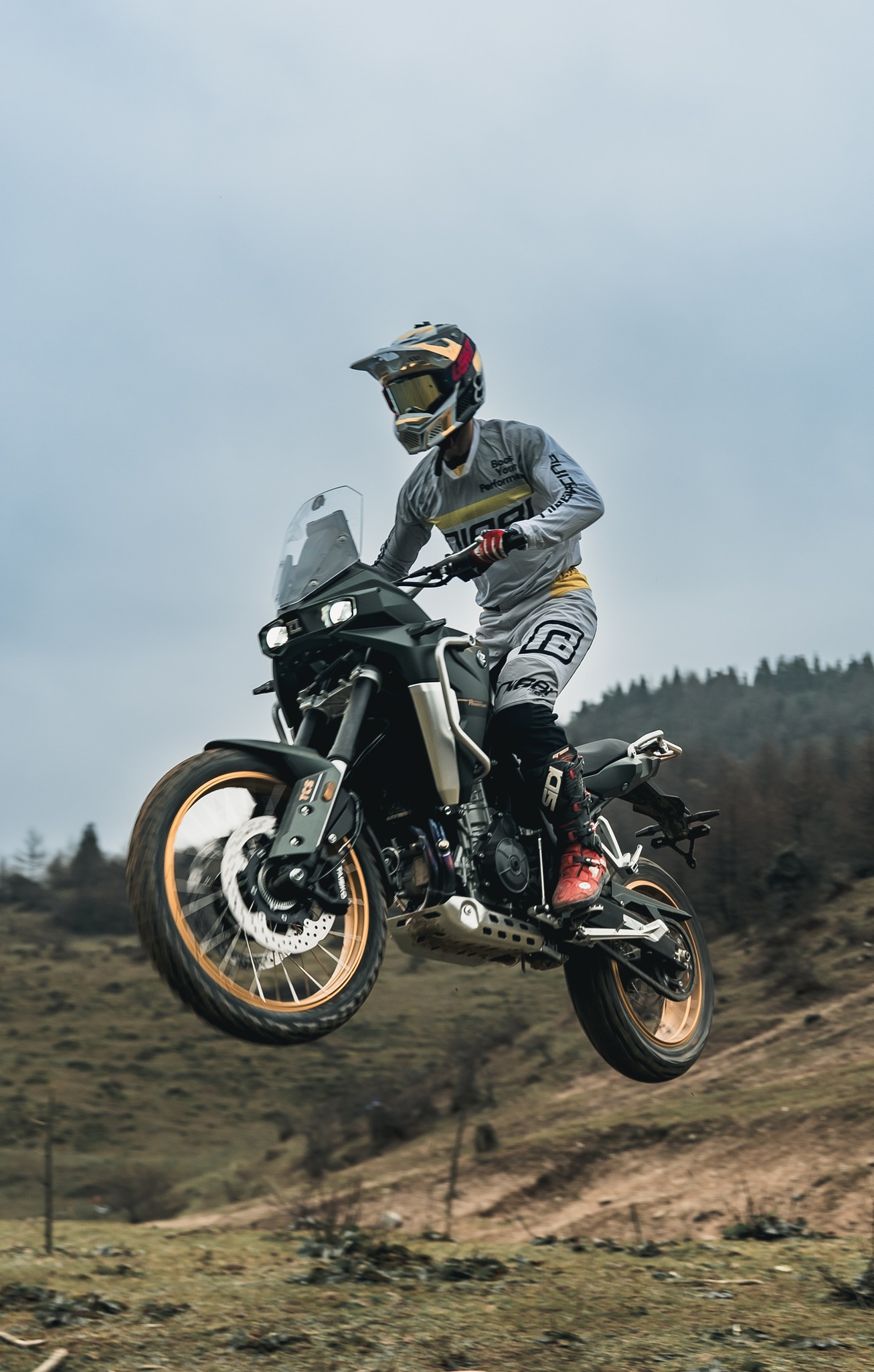 Trail Kove Moto 800X Pro en acción, suspendida en un salto con paisaje al fondo