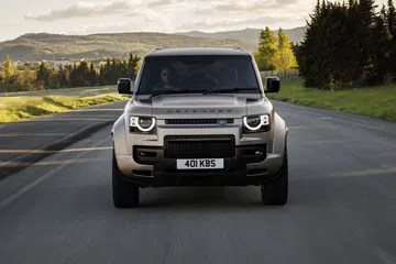 Vista frontal del Land Rover Defender en carretera, imponente y robusto.