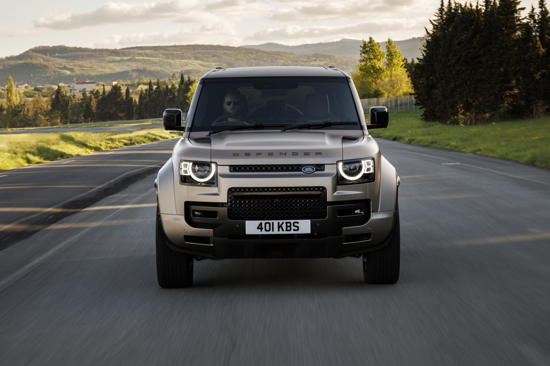 Vista frontal del Land Rover Defender en carretera, imponente y robusto.