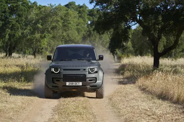 Vista en acción del Land Rover Defender por caminos de tierra, mostrando su capacidad todoterreno.