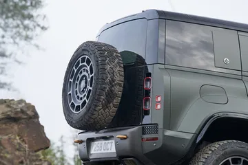 Vista trasera y lateral del robusto Land Rover Defender en terreno agreste