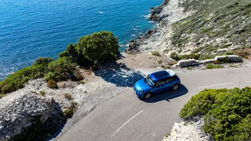 Vista aérea del Mini Cooper S 5 puertas en carretera costera, equilibrio perfecto entre tamaño y prestaciones.